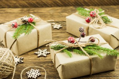 Sıfır israf noeli konsepti. El yapımı Noel hediye kutuları içinde köknar ağacı dalları ve kırmızı donmuş böğürtlenler var.