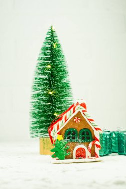 Çiçekli mini Noel ağacı, gignerbread evi ve beyaz arka planda hediye kutusu..