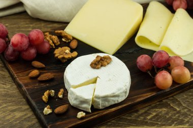 Tahtada değişik fındıklar ve olgun üzümlerle çeşitli peynirler var.