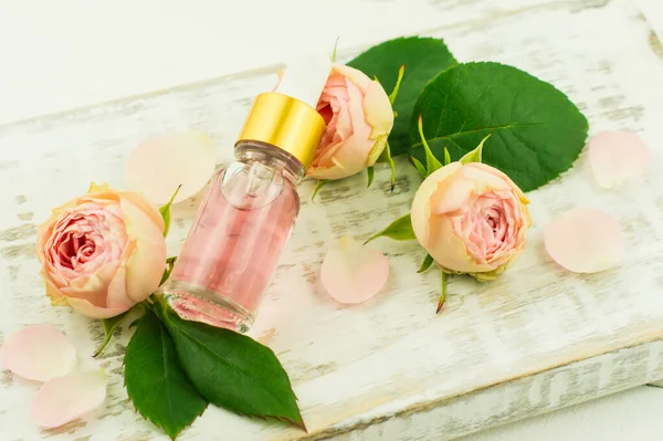 Auszug Aus Rosenblättern Einer Glaskosmetikflasche Vor Dem Hintergrund Einer Rosenknospe — Stockfoto