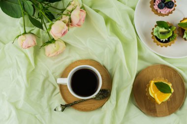 Yatakta kahvaltı. Bir fincan kahve, meyveli mini tortilla ve bir buket pembe gül. 8 Mart, Sevgililer Günü kutlaması konsepti