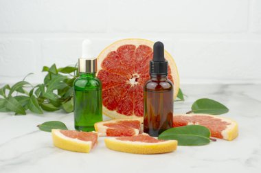 Yüz bakımı, aromaterapi ve stres giderici için greyfurt yağı içeren iki kozmetik şişe. beyaz mermer arkaplan.