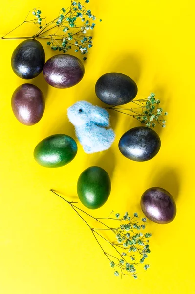 Mini composição de férias de Páscoa. ovos coloridos pintados, brinquedo de coelho e galhos de flores de primavera. vista superior. fundo amarelo. — Fotografia de Stock