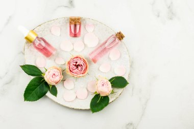 Orijinal seramik tabağın üst görüntüsü kozmetik gül yağı, gül suyu, tomurcuklar ve gül yapraklarıyla dolu.