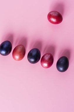 Paskalya bayramının mini kompozisyonu. Pembe arka planda çok renkli boyanmış yumurtalar. en üstteki görünüm