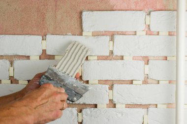 Usta yapıştırıcı çözeltiyi dekoratif fayansa bir spatula ile uyguluyor. iş bitirme konsepti