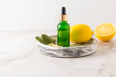 Yeşil camdan yapılmış bir kozmetik şişesi. İçine limon serumu konmuş. Organik öz bakım için. mermer arkaplan