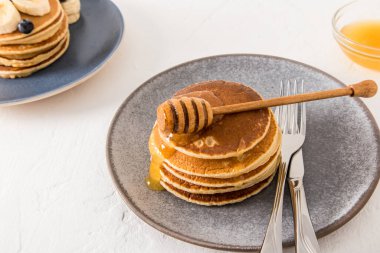 Gri bir tabakta, içinden bal akan bir yığın kalın krep. Sağlıklı lezzetli atıştırmalık konsepti