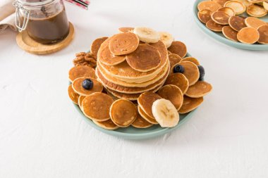 Böğürtlenli ve muzlu bir tabakta bir sürü ev yapımı krep. Tatlı tadı tamamlamak için çikolata ezmesi. beyaz arkaplan