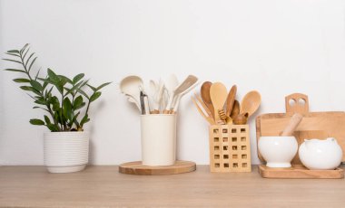 Mutfak ahşap tezgahı ve evde yemek pişirmek için çeşitli aletler. Seramik kaptaki yeşil çiçek