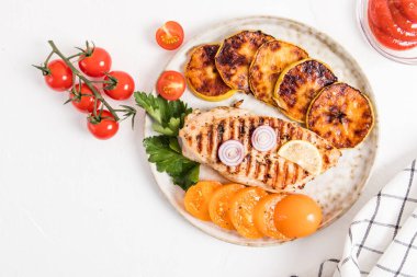 Izgara tavuklu fileto, kızarmış elma dilimleri, taze domates ve ketçap ile büyük bir tabak. beyaz arkaplan