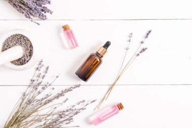 Lavana 'dan gelen kozmetik ürünlerle dolu birkaç cam şişenin üst görüntüsü. Vücut bakımı için organik kozmetik ürünleri. Kaplıca. beyaz tahta arkaplan