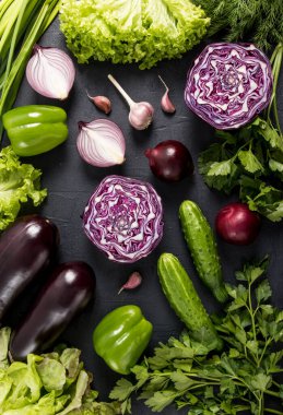 sebze dikey arkaplan. Siyah bir masada yeşil ve mor sebzeler. Düz stil. Üst Manzara. sağlıklı beslenme