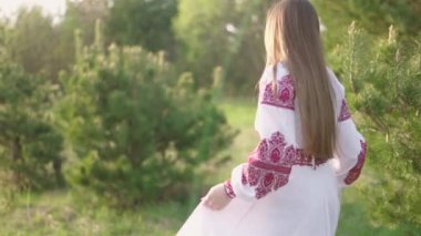 Vyshyvanka 'lı genç ve güzel Ukraynalı bir kadının 4K' lık geniş bir çekimi - Ukrayna ulusal kıyafetleri. Kırsal kesimde bir kadın. Ukrayna 'nın yanında dur
