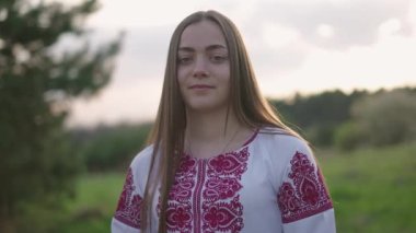 Vyshyvanka 'lı genç ve güzel Ukraynalı bir kadının 4K' lık geniş bir çekimi - Ukrayna ulusal kıyafetleri. Kırsal kesimde bir kadın. Ukrayna 'nın yanında dur