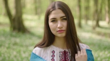 4k shot of young beautiful Ukrainian woman in vyshyvanka - ukrainian national clothes. She prays for Ukraine and holding flag - symbol of freedom and independence. Stand with Ukraine