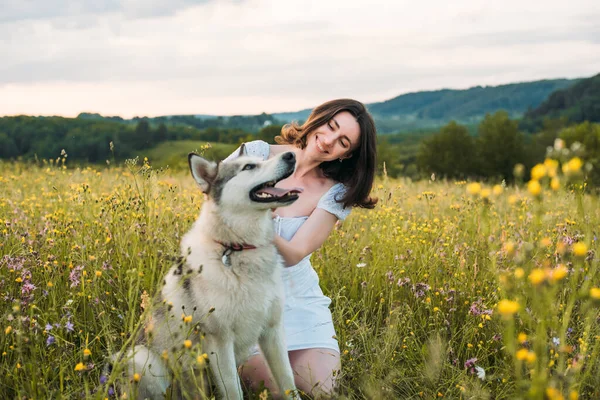 young cheerful woman in field with siberian husky dog