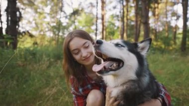4k slow motion shot of teenage girl playing and having fun with her siberian husky dog. Girl with dog in the forest