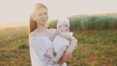 4k slow motion shot of mother and daughter having a picnic outdoors in the field. Playing and having fun with little baby . Happy family concept