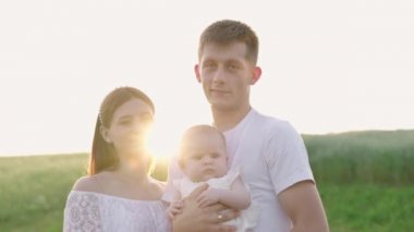 4k slow motion shot - Young family of three - mother, father and daughter having picnic outdoors during beautiful sunset. Slow living and happy family concept