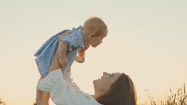 4k slow motion shot of mother and daughter having a picnic outdoors in the field. Playing and having fun with little baby . Happy family concept