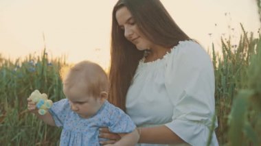 4k slow motion shot of mother and daughter having a picnic outdoors in the field. Playing and having fun with little baby . Happy family concept