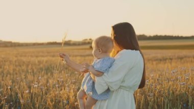 4k slow motion shot of mother and daughter having a picnic outdoors in the field. Playing and having fun with little baby . Happy family concept