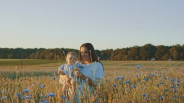 4k slow motion shot of mother and daughter having a picnic outdoors in the field. Playing and having fun with little baby . Happy family concept