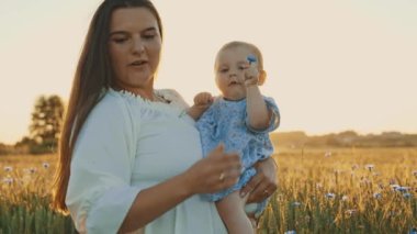 4k slow motion shot of mother and daughter having a picnic outdoors in the field. Playing and having fun with little baby . Happy family concept