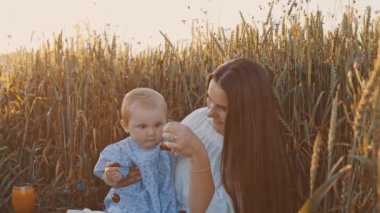 4k slow motion shot of mother and daughter having a picnic outdoors in the field. Playing and having fun with little baby . Happy family concept