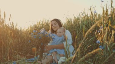 4k slow motion shot of mother and daughter having a picnic outdoors in the field. Playing and having fun with little baby . Happy family concept