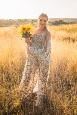 Gün batımında kırsalda mutlu ve hamile bir kadının portresi.