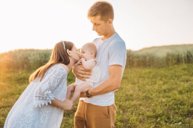 Üç kişilik genç bir aile. Anne, baba ve kız güzel günbatımında eğleniyorlar. Yavaş yaşam ve mutlu aile kavramı 