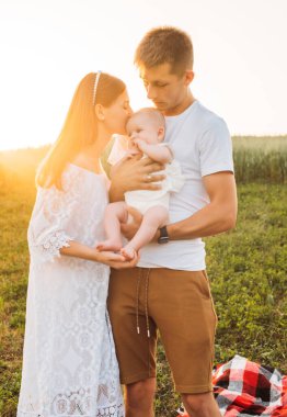 Üç kişilik genç bir aile. Anne, baba ve kız güzel günbatımında eğleniyorlar. Yavaş yaşam ve mutlu aile kavramı 