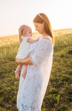 Anne ve kızı tarlada poz veriyor. Küçük bebekle oynamak ve eğlenmek. Mutlu aile kavramı 
