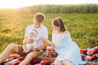 Üç kişilik genç bir aile. Anne, baba ve kız gün batımında dışarıda piknik yapıyorlar. Yavaş yaşam ve mutlu aile kavramı