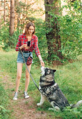 Genç kız Sibirya köpeğiyle oynuyor ve eğleniyor. Ormanda köpekli bir kız