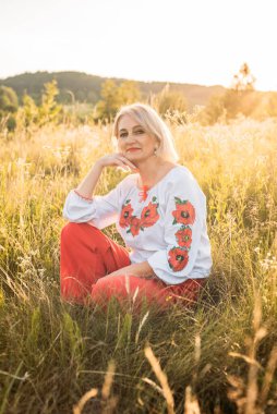 Mutlu, neşeli, olgun bir kadının güzel günbatımında taşrada portresi.