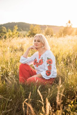 Mutlu, neşeli, olgun bir kadının güzel günbatımında taşrada portresi.