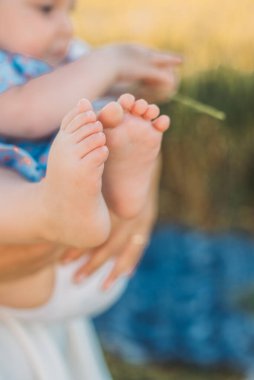 Açık havada annesinin kollarında mutlu küçük bir kızın portresi.