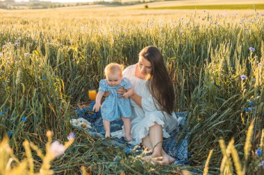 Anne ve kızı dışarıda piknik yapıyorlar. Küçük bebekle oynamak ve eğlenmek. Mutlu aile kavramı