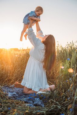 Anne ve kızı dışarıda piknik yapıyorlar. Küçük bebekle oynamak ve eğlenmek. Mutlu aile kavramı