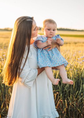 Anne ve kızı dışarıda, tarlada. Küçük bebekle oynamak ve eğlenmek. Mutlu aile kavramı