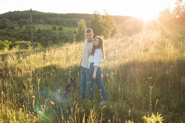 Genç mutlu çift, güzel günbatımında kırsal alanda buldoglarıyla eğleniyor.