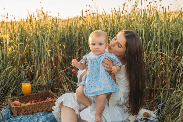 Anne ve kızı dışarıda piknik yapıyorlar. Küçük bebekle oynamak ve eğlenmek. Mutlu aile kavramı