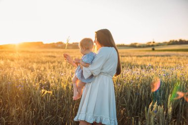 Anne ve kızı dışarıda, tarlada. Küçük bebekle oynamak ve eğlenmek. Mutlu aile kavramı