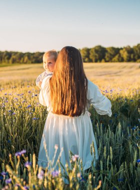 Anne ve kızı dışarıda, tarlada. Küçük bebekle oynamak ve eğlenmek. Mutlu aile kavramı