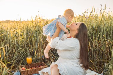 Anne ve kızı dışarıda piknik yapıyorlar. Küçük bebekle oynamak ve eğlenmek. Mutlu aile kavramı
