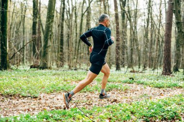 Güzel bahar ormanlarında koşan sporcu adamın geniş açılı görüntüsü. Spor ve sağlık konsepti