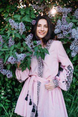 Çiçek açan leylak ağacının yanında vyshyvanka giyen genç ve güzel bir kadın. Ukrayna ulusal kıyafetleri..